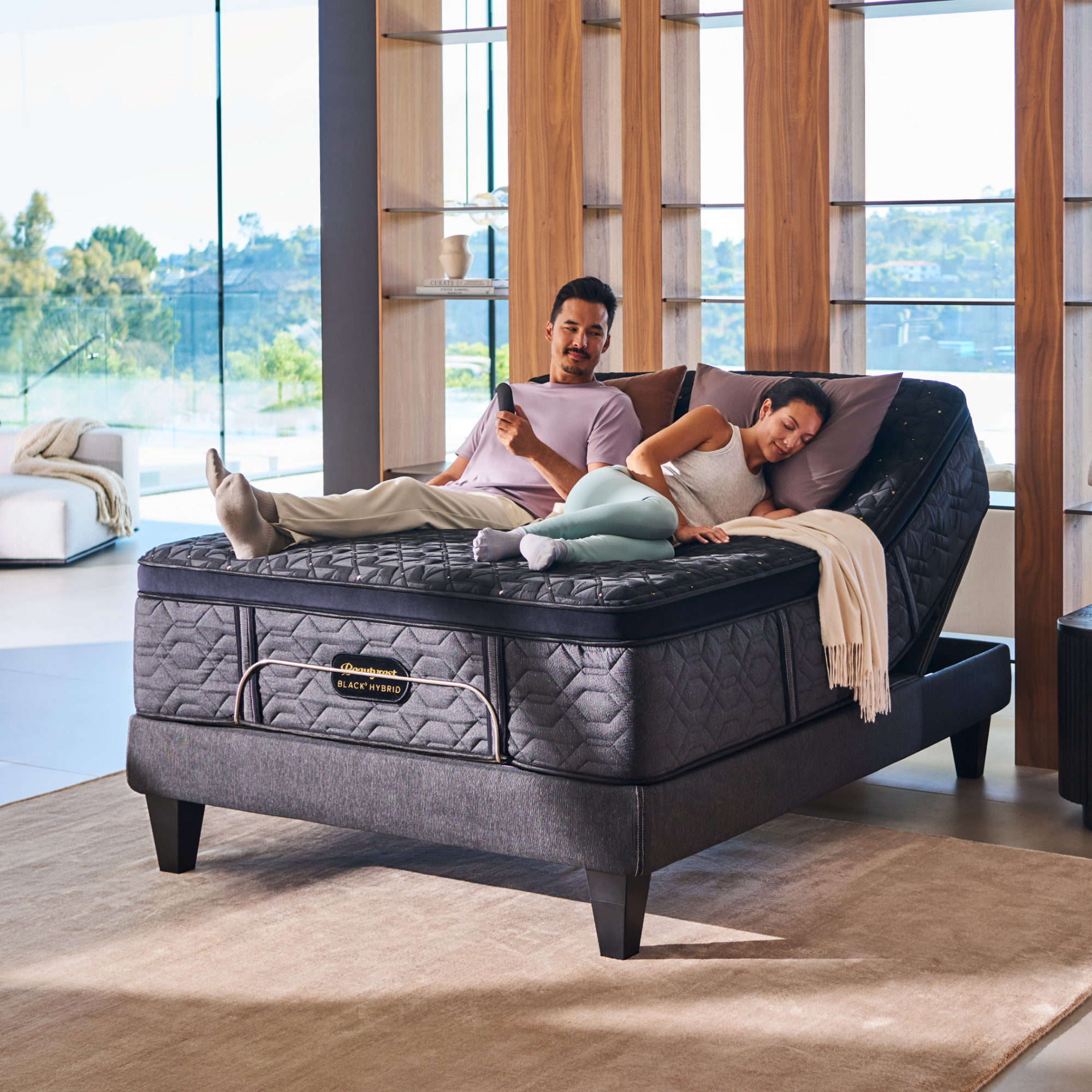 A couple laying on a Beautyrest Black Series Four with an adjustable base